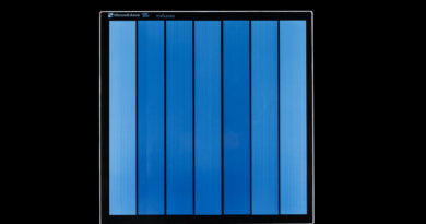 A piece of Project Silica glass storage media written with data, shown as vertical color bars in shades of blue