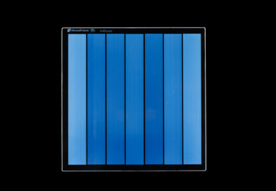 A piece of Project Silica glass storage media written with data, shown as vertical color bars in shades of blue