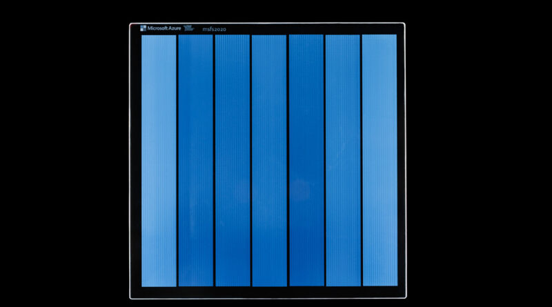 A piece of Project Silica glass storage media written with data, shown as vertical color bars in shades of blue
