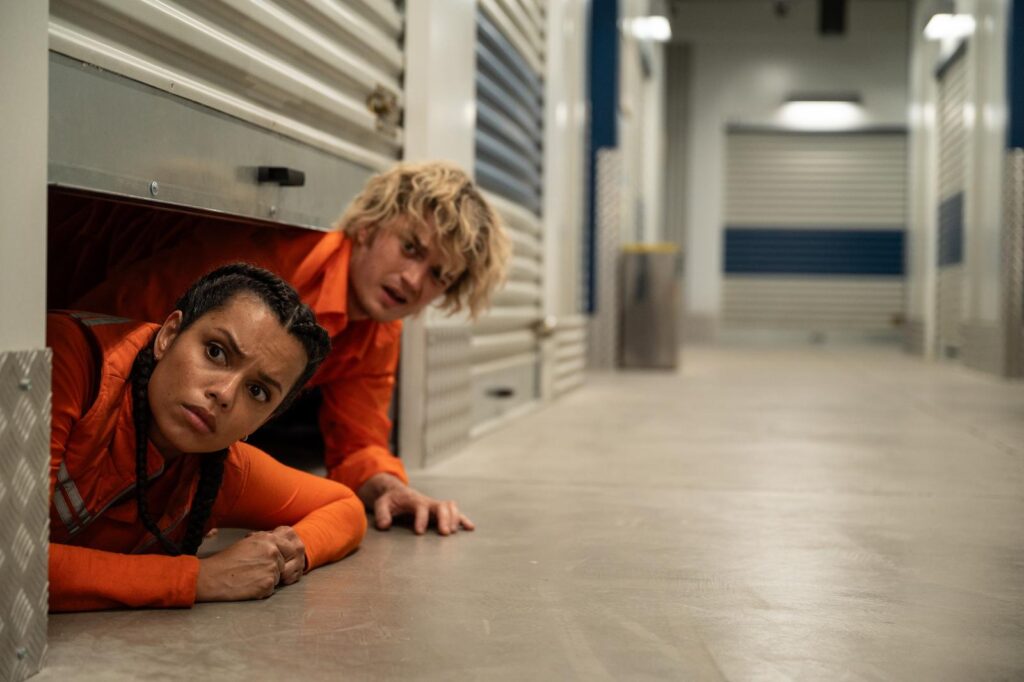 Naomi and Teacake peek out from under a storage unit door in Cold Storage