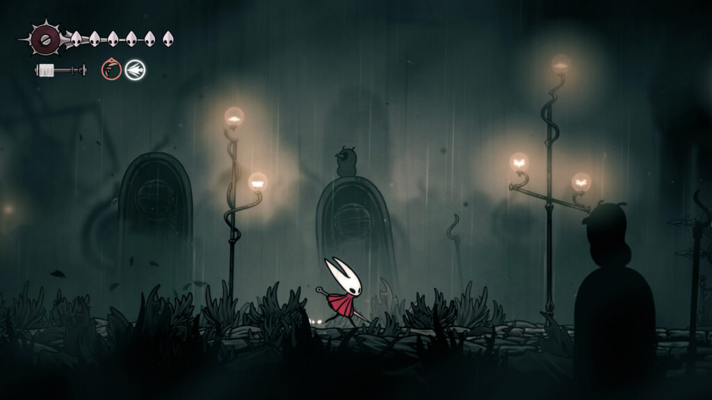 Hornet walking through a dark, lamp-lit town in Hollow Knight: Silksong